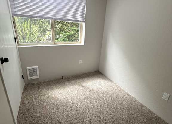 A room with a window covered by blinds and a door with a lock.