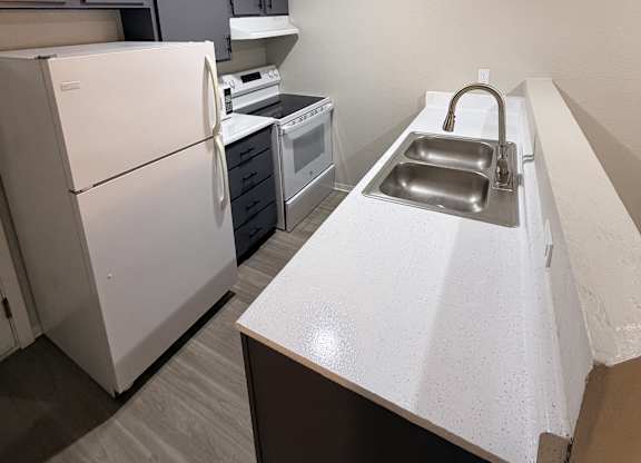 A white refrigerator is in a kitchen with a white counter.