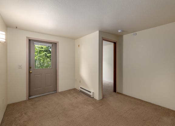 A room with a carpeted floor and a door leading outside.