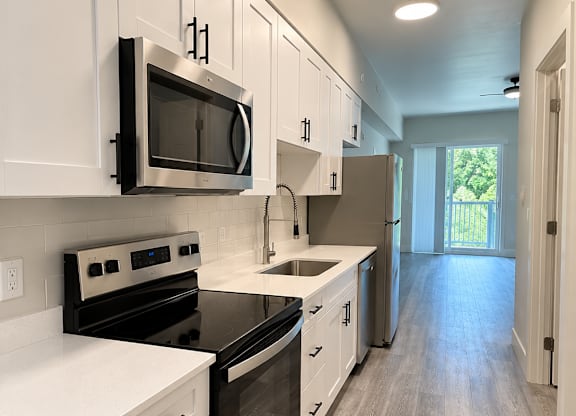 A kitchen with white cabinets and a black microwave.