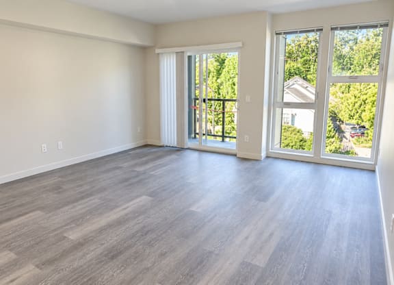 A room with light wood flooring and sliding glass doors.