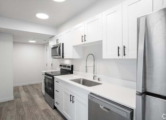 A modern kitchen with white cabinets and stainless steel appliances.