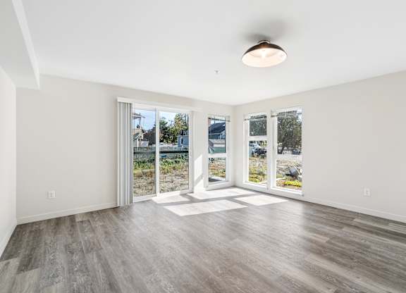 A spacious room with a sliding glass door leading to a balcony.