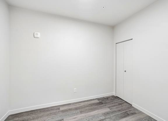 A room with a white door and a grey floor.