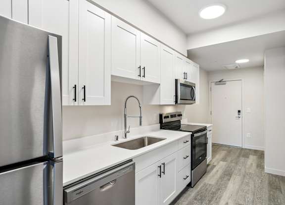 A kitchen with white cabinets and a stainless steel refrigerator.
