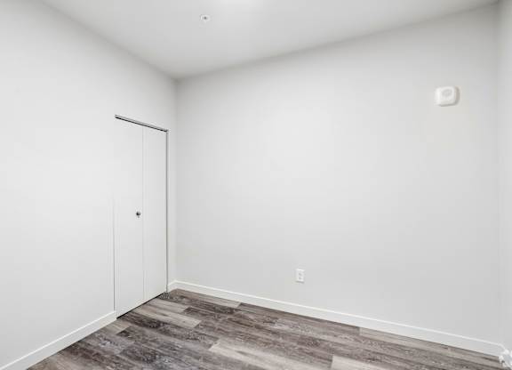 A room with a white door and a grey floor.