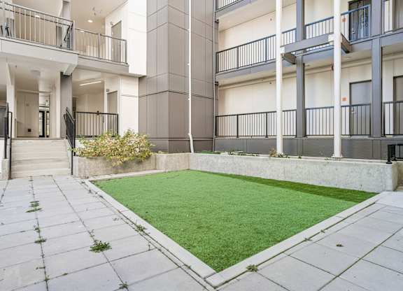 A courtyard with a green lawn surrounded by apartment buildings.