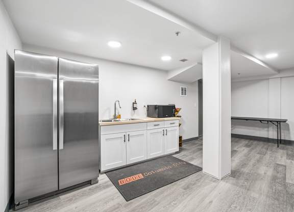 A modern kitchen with a stainless steel refrigerator and white cabinets.