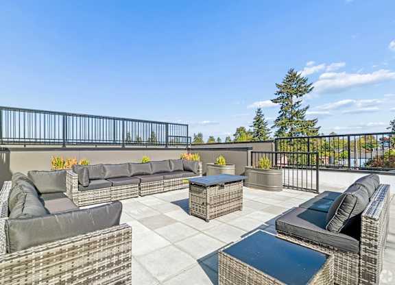 A patio with black metal railings and grey wicker furniture.