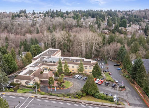 an aerial view of a building with a parking lot and trees