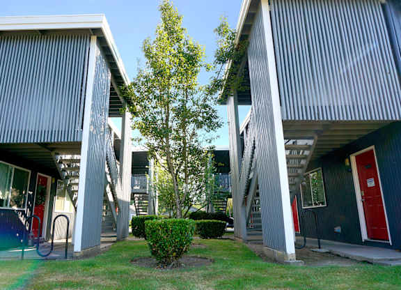 A modern building with a blue exterior and a tree in front.
