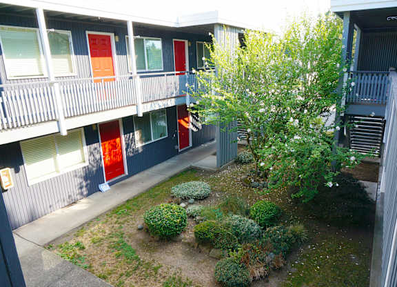 A balcony of a building with red doors and plants in front.