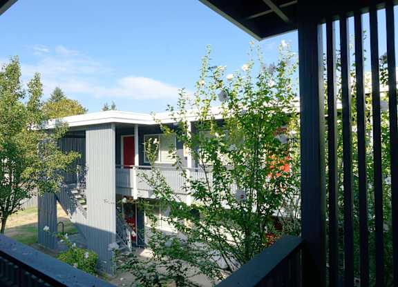 A house with a red door is seen through a window.