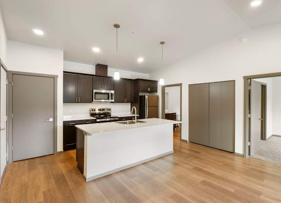 A modern kitchen with a white island and wooden floors.