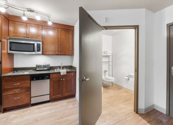 a kitchen with wooden cabinets and stainless steel appliances and a door to a bathroom