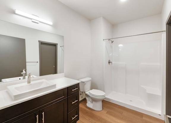 A white bathroom with a sink, toilet, and shower.