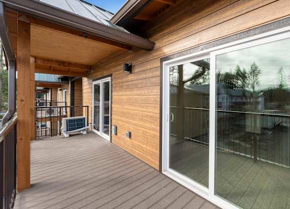 A wooden deck with a glass door leading to a patio.