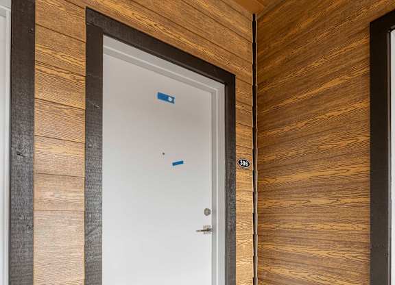 A white door is in a room with wooden walls.