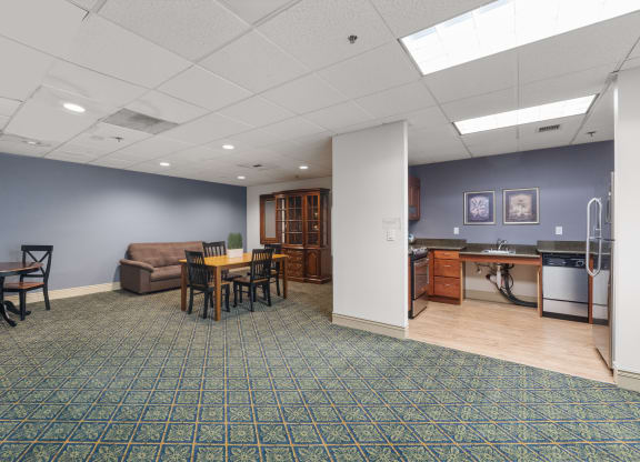 a community room with a kitchen and a table and chairs
