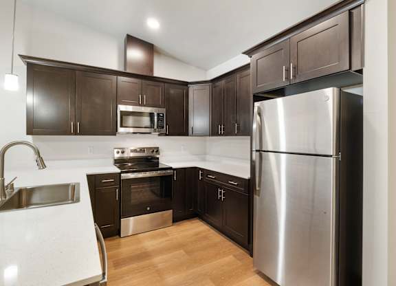 A modern kitchen with dark brown cabinets and stainless steel appliances.