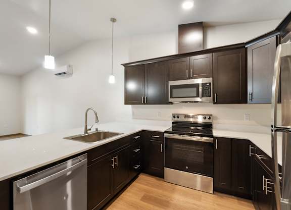 A modern kitchen with black cabinets and stainless steel appliances.