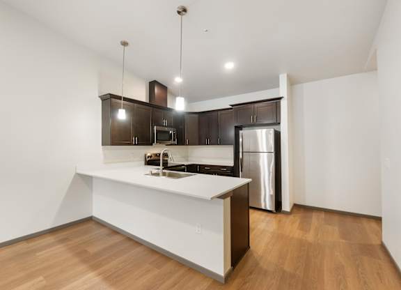 A modern kitchen with wooden floors and stainless steel appliances.