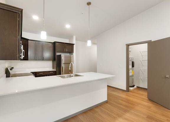A modern kitchen with a white countertop and dark brown cabinets.
