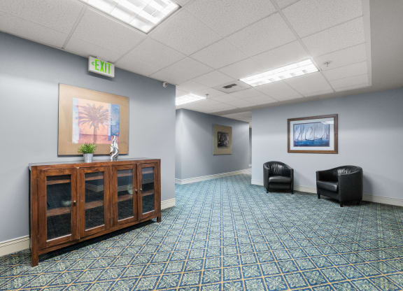 an empty waiting room with a cabinet and two chairs