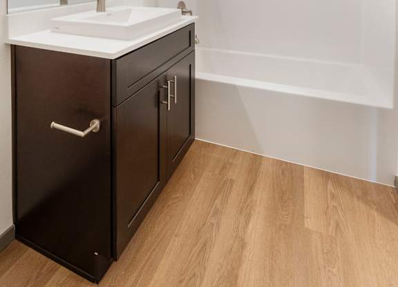 A modern bathroom with a white sink and black cabinetry.