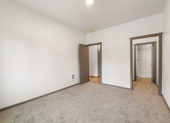 A room with a carpeted floor and three doors.