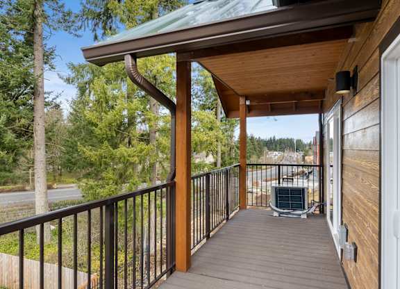 A wooden deck with a metal railing and a green roof.