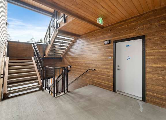 A wooden staircase with a metal railing leads to a door.