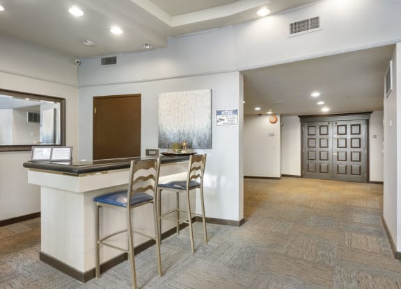 a lobby with a bar and two stools in front of a counter
