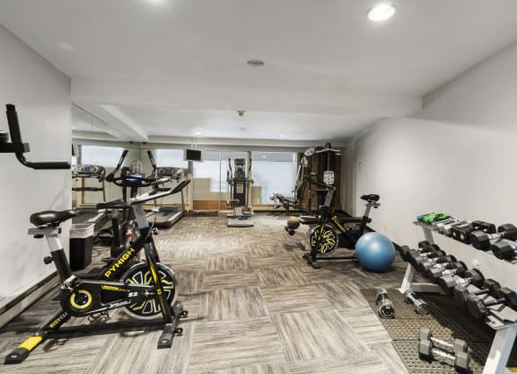 a gym with weights and bikes in the corner of a room
