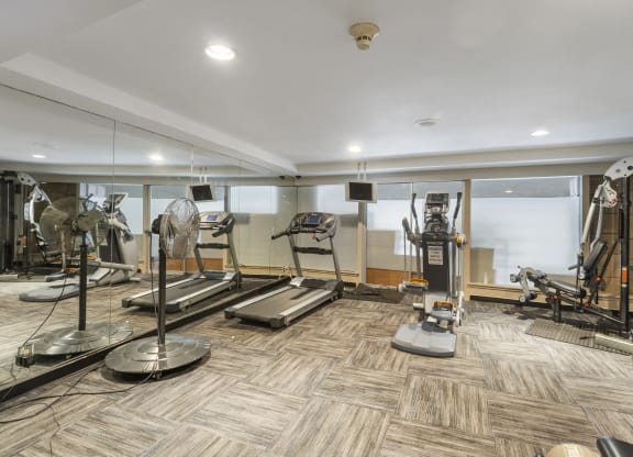 a gym with treadmills and other exercise equipment on a wooden floor