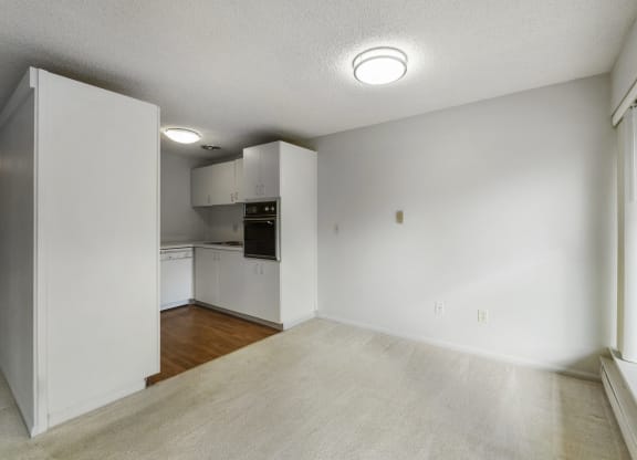 an empty living room and kitchen with white walls and wood floors