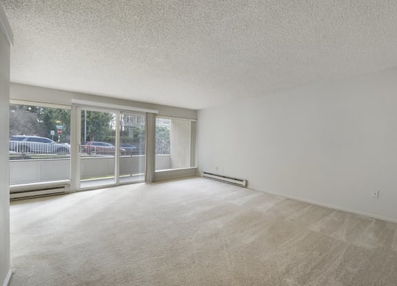 the living room of an apartment with a large window and white walls