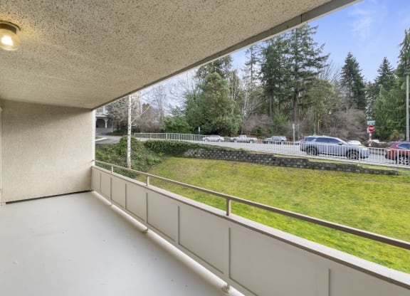 a balcony with a view of a parking lot and a grass field