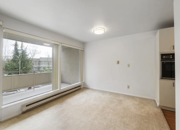 an empty living room with a large window and white walls
