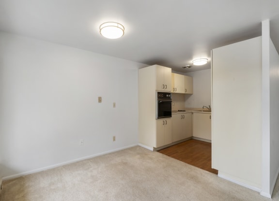 an empty living room and kitchen with white walls and wood flooring