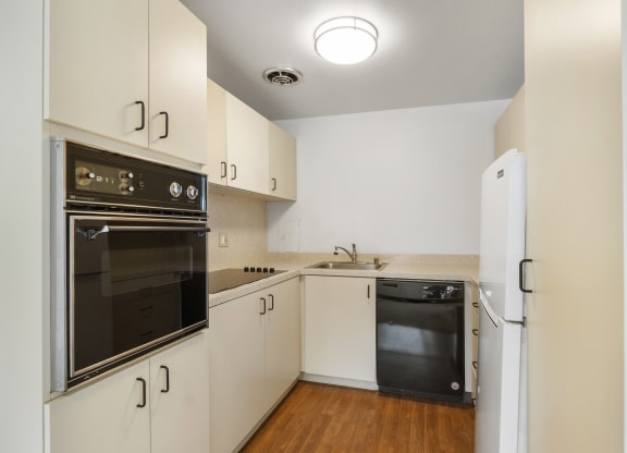 a kitchen with white cabinetry and black appliances and a refrigerator