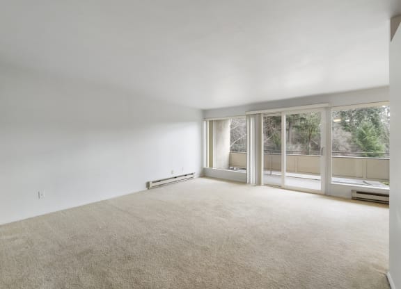 an empty living room with large windows and a carpeted floor