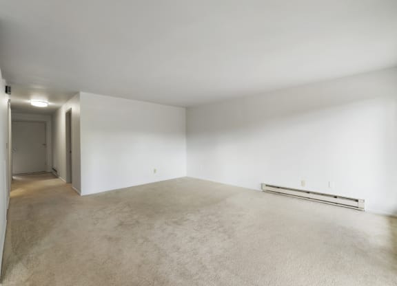 the living room and dining room of an empty house with white walls and carpet