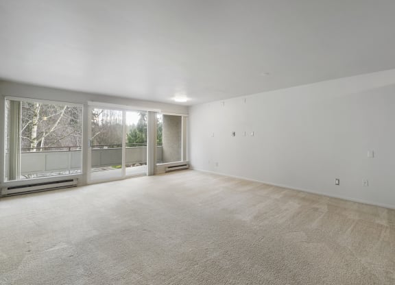 an empty living room with a large window and carpeting