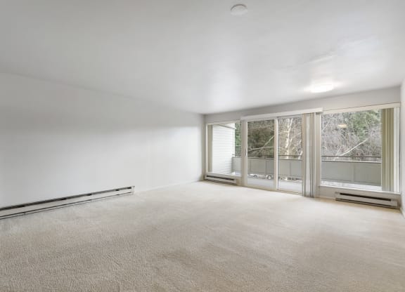an empty living room with a large window and white walls
