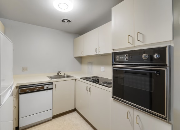 a kitchen with white cabinets and black appliances and a refrigerator