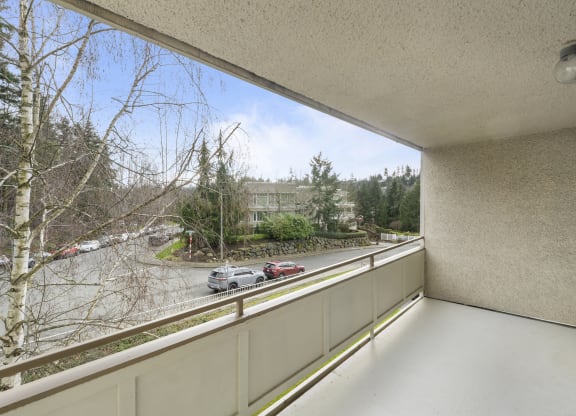 a balcony with a view of a parking lot and trees