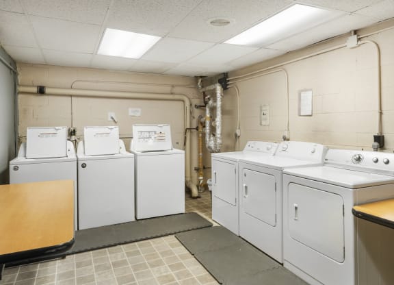 a row of washers and dryers in a laundry room with four washes