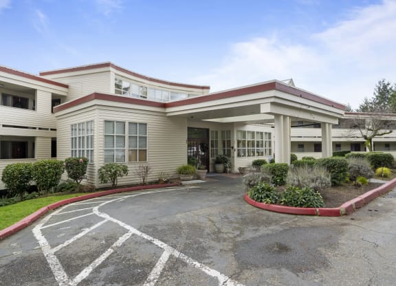 the exterior of a hotel with a parking lot and a building
