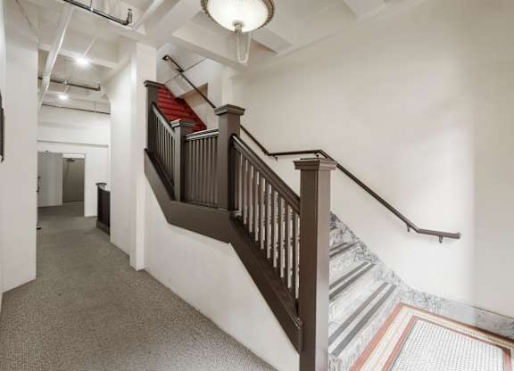 A staircase with a wooden banister and a striped carpet.